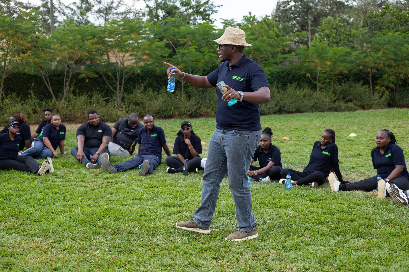A man addressing participants seated in a circle outdoors