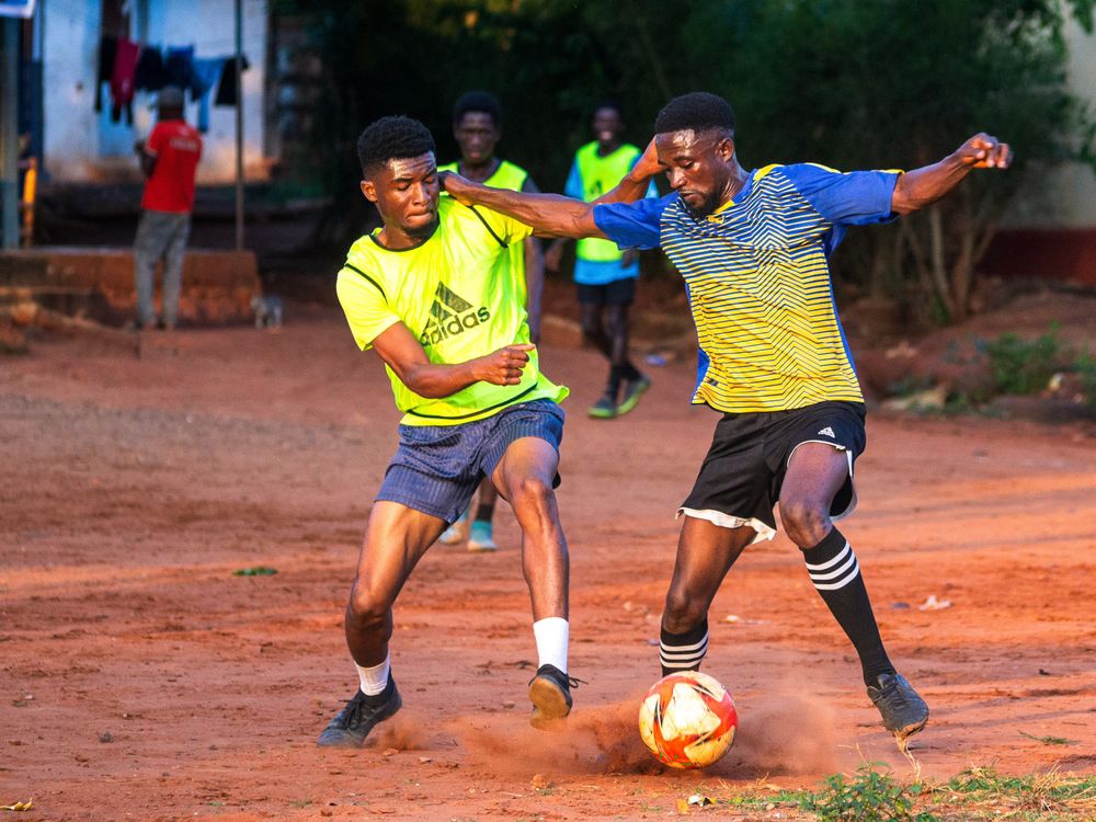 Football players contesting possession on a pitch in Accra